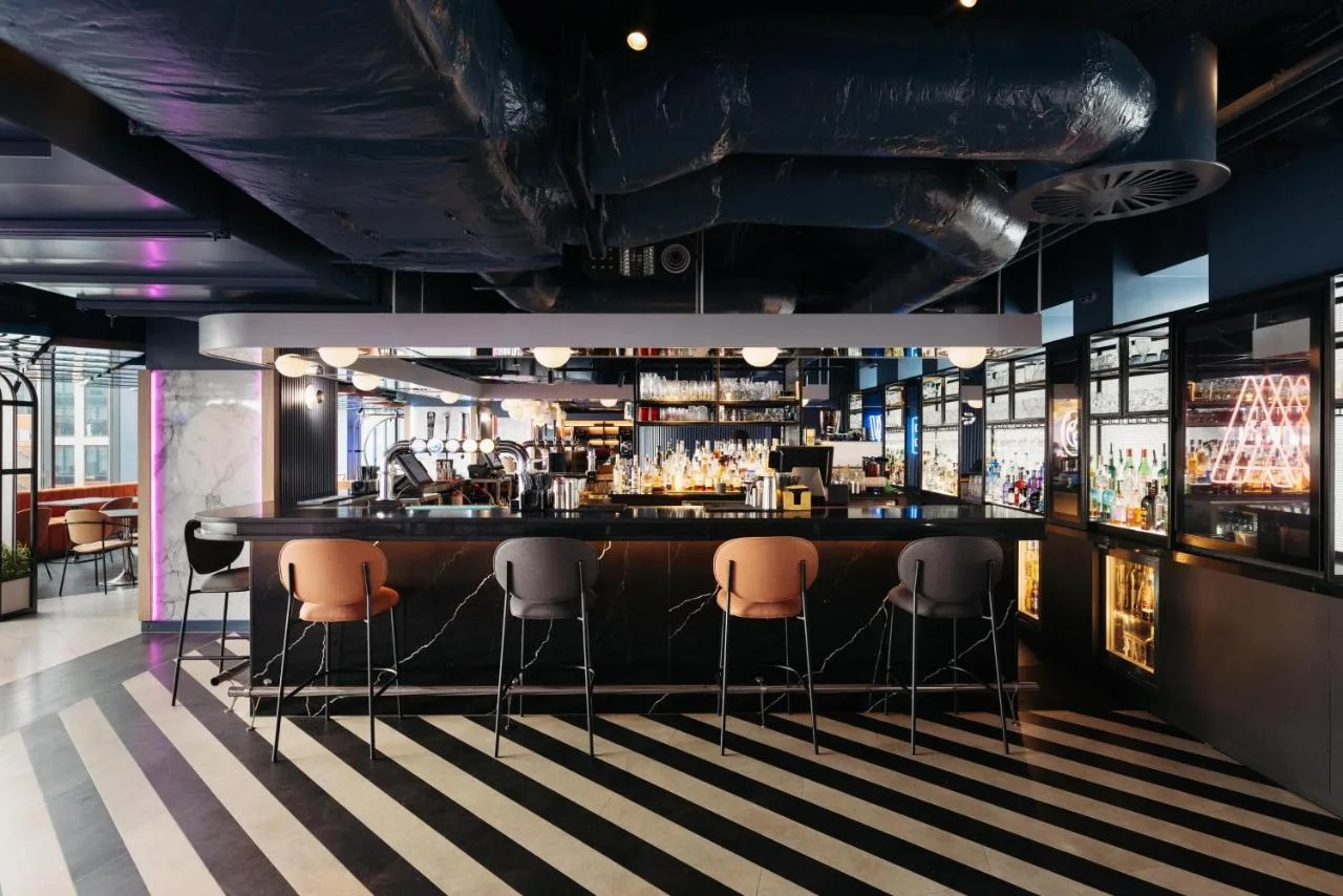 a bar with four stools in a room at Yotel Glasgow in Glasgow