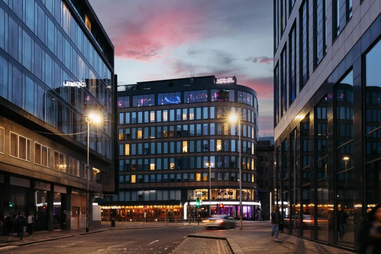 a city street at night with buildings and a car at Yotel Glasgow in Glasgow