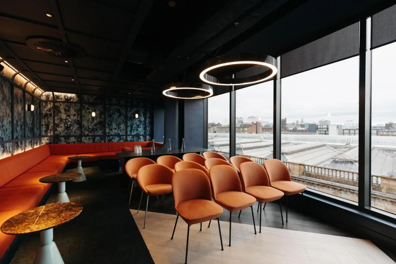 a restaurant with orange chairs and a bar with a view at Yotel Glasgow in Glasgow