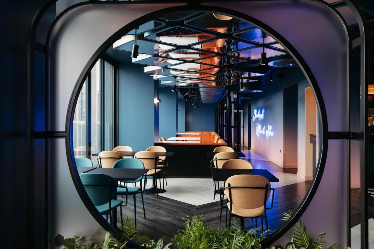 a mirror in a room with chairs and a bar at Yotel Glasgow in Glasgow